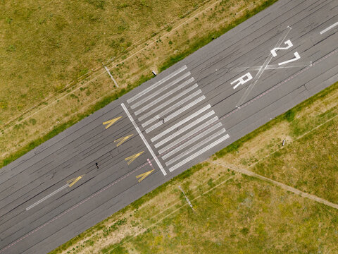 Aerial view of a runway with prominent markings cutting through fields of green and yellow grass, Tempelhofer Damm, Berlin, Berlin, Germany.