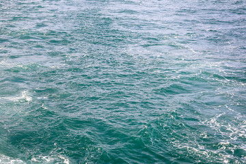 Close up photo of boat white wake.Foamy trail left behind by a boat cuts through the deep teal water