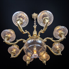 Luxurious vintage chandelier with ornate brass arms and clear cut-glass shades, glowing warm...