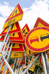 Traffic signs indicating road conditions and warnings at a construction site in a sunny outdoor...