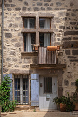 Vieille maison en pierre d'un village typique du Sud de la France avec ses tours de fenêtre en pierre du Moyen-âge et ses volets bleus lavande.
