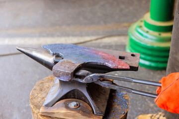 Skilled blacksmith uses tongs to manipulate hot metal on an anvil in during axe making