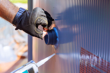 Worker applies sealant filtration system to swimming pool while wearing gloves during construction...