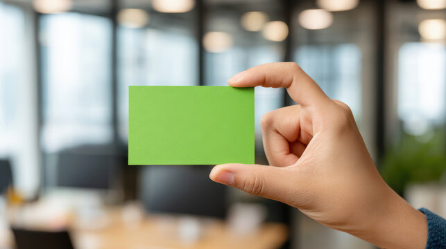 Hand holding green business card in modern office environment professional photography contemporary design close-up view