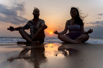 Couple meditating on the beach at sunrise: embracing serenity and mindfulness