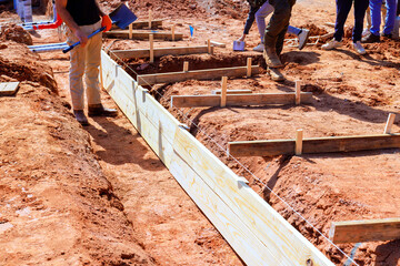 Workers are assembling wooden forms for foundation of new structure at construction site