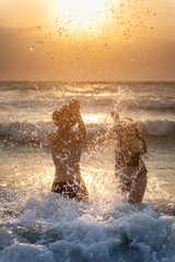 Obraz premium Couple enjoying sunrise splash on the beach
