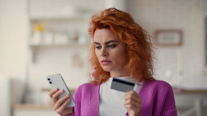 Caucasian puzzled worried girl female woman buyer try to pay online with mobile phone bank app...
