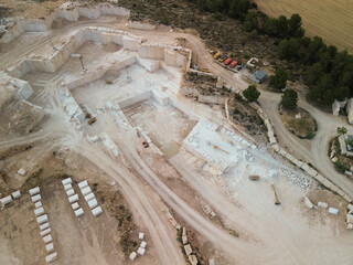 Aerial view of a large light‑stone quarry featuring heavy machinery at work