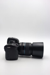 Digital camera with a large lens positioned horizontally on a plain background showcasing its design and features