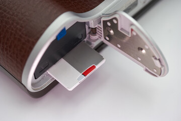 Close up view of a camera revealing the memory card compartment with a silver and red memory card inserted