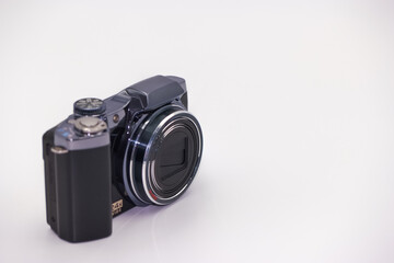 Compact digital camera positioned on a white surface showcasing modern design with clear lens and...