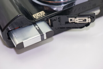 Close up view of a digital camera battery compartment showing battery insertion process