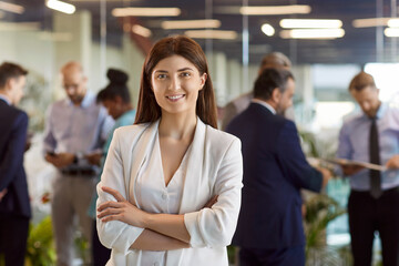 Confident businesswoman standing in the hall with her arms crossed. Portrait of a beautiful woman...