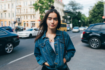 Fototapeta premium Woman in a blue denim jacket stands on a city street