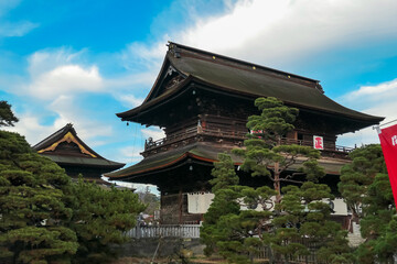 The imposing Sanmon Gate of Zenkoji Temple stands majestically under a vibrant blue sky in Nagano,...