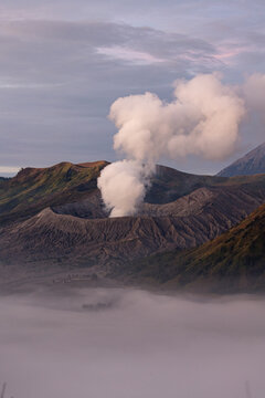 View of wisps of smoke curling from a volcanic crater, contrasting with the soft sea of clouds below, a natural spectacle, Mount Bromo, East Java, Indonesia.
