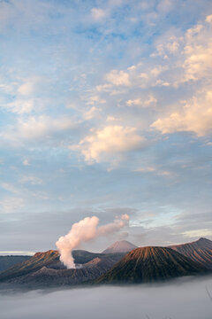 View of dramatic volcanic peaks piercing through a sea of ethereal mist under a pastel sky, a breathtaking panorama, Mount Bromo, East Java, Indonesia.