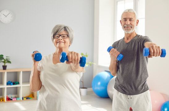 Happy elderly couple in rehabilitation center doing exercises with dumbbells, close-up. Senior people doing sports indoors. Concept older adults, grandparents family, active rehabilitation