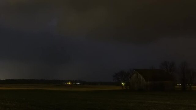 Dramatic lightning storm over a rural landscape with a barn.