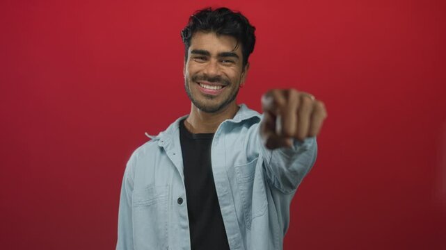 Man smiling and pointing finger at camera while making eye contact in studio; confidence inspiration connection.