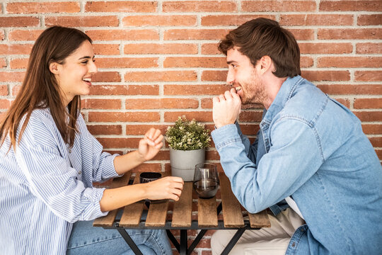 Young couple or friends Eva and Nil chatting happily at table – casual meeting, friendly conversation, relationship, teamwork and social connection concept