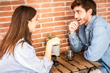 Young couple or friends Eva and Nil chatting happily at table – casual meeting, friendly...