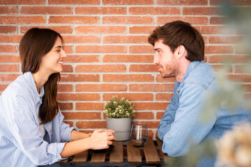 Young couple or friends Eva and Nil chatting happily at table – casual meeting, friendly...