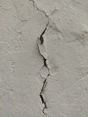 Deep vertical crack in light cement wall for structural detail, aging surfaces and mapping overlays