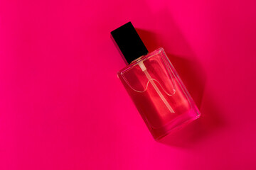 Close-up of a transparent glass perfume bottle. A vial of fragrant water on a pink background....