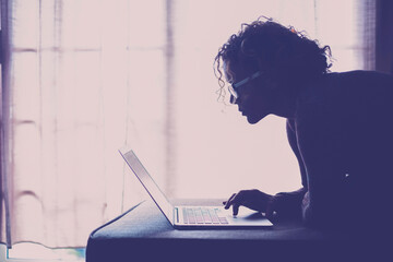 Curly-haired woman in her 40s using a laptop at home with varied expressions. Remote work, digital...