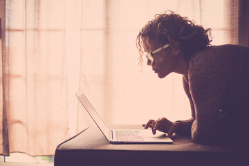 Curly-haired woman in her 40s using a laptop at home with varied expressions. Remote work, digital...