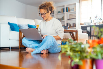 Curly-haired woman in her 40s using a laptop at home with varied expressions. Remote work, digital...