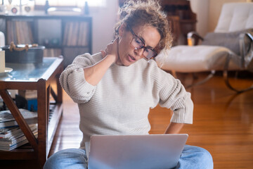 Curly-haired woman in her 40s using a laptop at home with varied expressions. Remote work, digital...