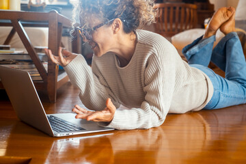 Curly-haired woman in her 40s using a laptop at home with varied expressions. Remote work, digital...