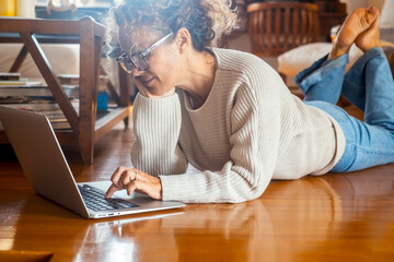 Curly-haired woman in her 40s using a laptop at home with varied expressions. Remote work, digital...