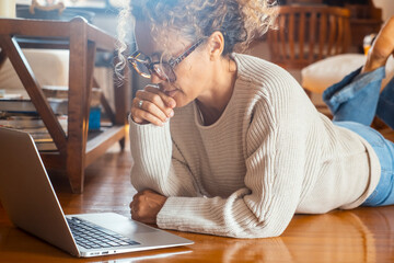 Curly-haired woman in her 40s using a laptop at home with varied expressions. Remote work, digital...
