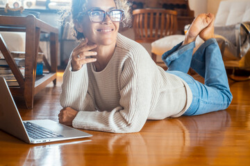 Curly-haired woman in her 40s using a laptop at home with varied expressions. Remote work, digital...