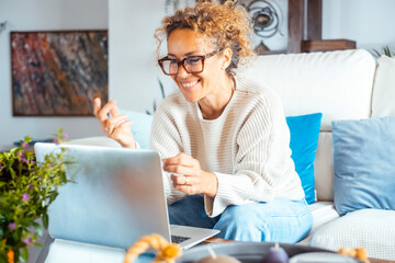 Curly-haired woman in her 40s using a laptop at home with varied expressions. Remote work, digital...