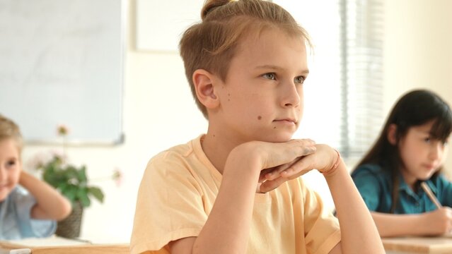 Smart elementary student looking at teacher while attend in classroom. Diverse smart student sitting at classroom while listening teacher explain about classwork or test. Education concept. Pedagogy.