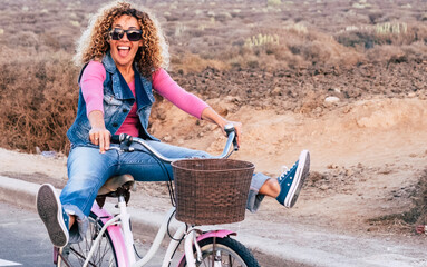 Smiling midlife woman riding a city bicycle outdoors on a sunny day. Leisure time, healthy...