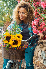 Smiling curly-haired woman in her 40s riding a city bicycle outdoors. Healthy lifestyle,...