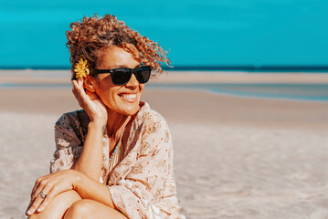 Portraits of a joyful curly-haired woman with sunglasses enjoying a summer day at the beach. Happy...