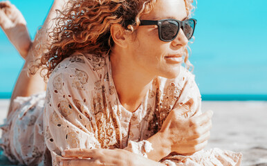 Portraits of a joyful curly-haired woman with sunglasses enjoying a summer day at the beach. Happy...
