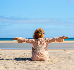 Portraits of a joyful curly-haired woman with sunglasses enjoying a summer day at the beach. Happy...
