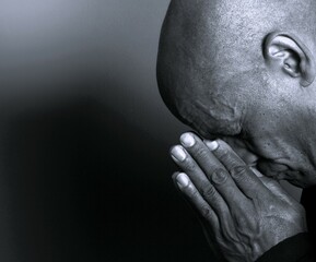 man praying to god with hands together Caribbean man praying with black background with people stock photo stock image