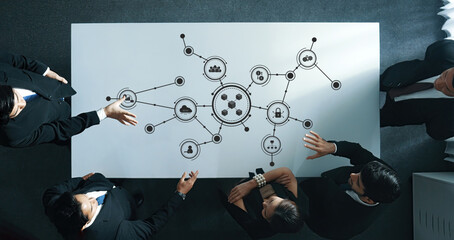 Aerial view of business professionals collaborating at a modern conference table. The image illustrates a digital network concept symbolizing connections and data flow. Amity