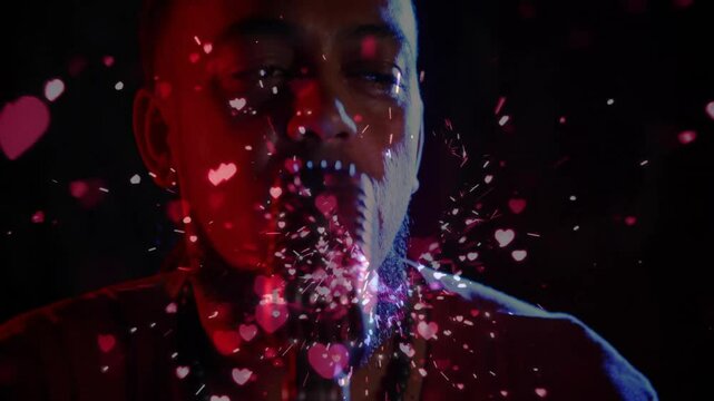 Hearts drifting across red-lit stage sparking music as vocalist leaning into vintage mic singing