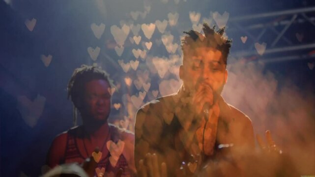 Lead singer entering heart bokeh gripping mic while singing on music stage as drummer clapping drum
