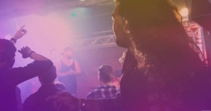 Beat intensifying driving two men dancing front row in music venue, stage lights pulsing with haze